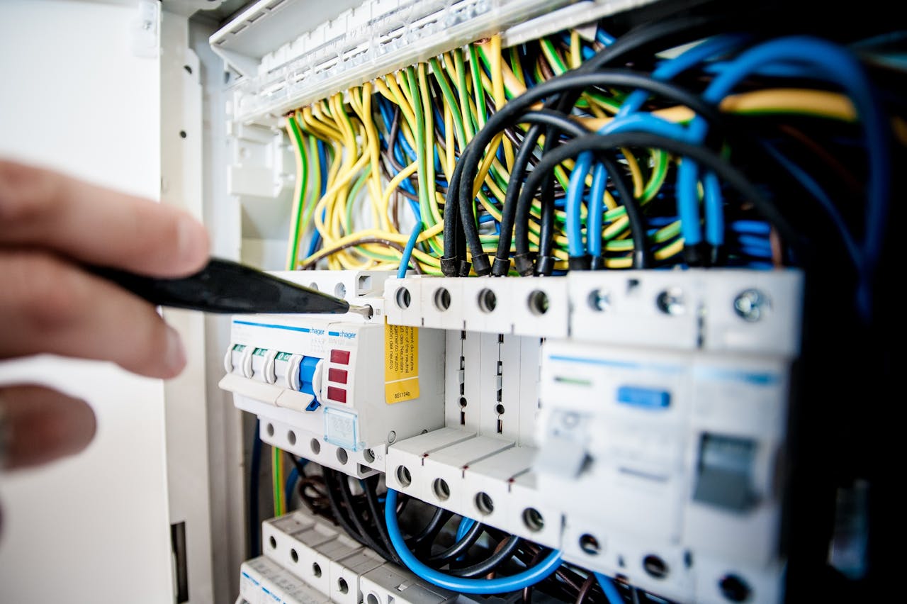 The Art of Drawing Readers In: Your attractive post title goes here Hand of electrician working on a circuit breaker panel with colorful wires, ensuring safe electrical connections.